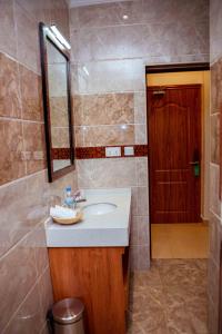 ein Badezimmer mit einem Waschbecken, einem Spiegel und einer Tür in der Unterkunft Urban Park Suites in Kigali