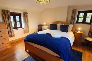 um quarto com uma cama grande e um cobertor azul em Westdale Cottage, Elton in the Peak District em Elton