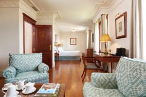 a living room with two chairs and a table and a bed at Hotel Inglaterra in Seville