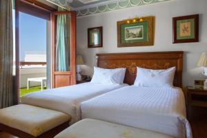 een slaapkamer met 2 bedden en een groot raam bij Hotel Inglaterra in Sevilla