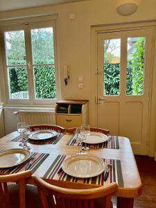 a dining room table with chairs and plates and windows at L'Annexe du 8 in Besançon