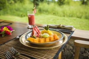 a plate of fruit on a table with a drink at Gal Oya Lodge in Galgamuwa
