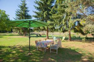 a table and chairs under a green umbrella in a park at le bon chemin roulotte in Sainte-Nathalène