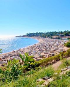 Domina Coral Bay Resort &casino في Dawwār Ruḩayyim: شاطئ به الكثير من المظلات والمحيط