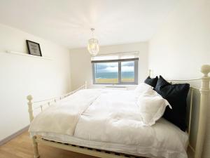 una camera bianca con un grande letto con finestra di 18 Coastline apartment a Newquay