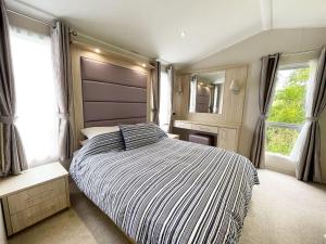 1 dormitorio con 1 cama con edredón de rayas y 2 ventanas en 11 Porth Valley Retreat, en Newquay Bay Resort