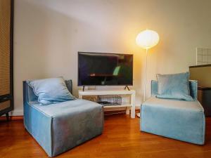 a living room with two blue chairs and a flat screen tv at Serviced Apartement Xanthurus in Schwelm