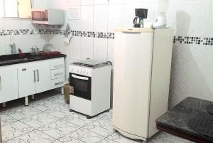 a kitchen with a white refrigerator and a stove at Apto Aeroporto Macae in Macaé
