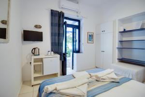1 dormitorio con paredes blancas y 1 cama con toallas. en Agriolykos Pension, en Agios Kirykos