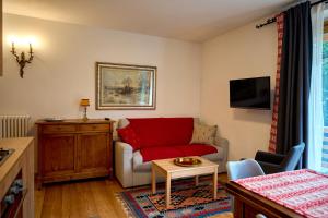 ein Wohnzimmer mit einem roten Sofa und einem Tisch in der Unterkunft Casa al Sole Apt 1 in Pinzolo