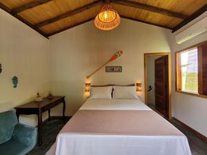 a bedroom with a bed and a table and a lamp at Bons Ventos Camping e Glamping in Barra Grande