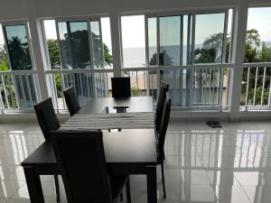 a dining table and chairs in a room with windows at Swiss Cottage in Kribi