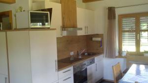 eine Küche mit weißen Schränken, einer Spüle und einer Mikrowelle in der Unterkunft Ferienwohnung Familie Köck in Mauth