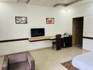 Schlafzimmer mit einem Bett, einem Schreibtisch und einem TV in der Unterkunft Hotel Whistling Greens in Moga