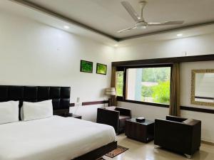 1 Schlafzimmer mit einem Bett, 2 Stühlen und einem Fenster in der Unterkunft Hotel Whistling Greens in Moga