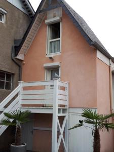 a house with a white balcony and two palm trees at Résidence Ana in Bagnères-de-Bigorre