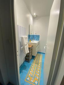 ein Badezimmer mit einem Waschbecken und einem blauen und gelben Boden in der Unterkunft L'Escale ZEN in Tulle