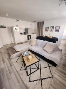 ein Wohnzimmer mit einem großen Sofa und einem Tisch in der Unterkunft Appartement cosy et chaleureux in Dunkerque