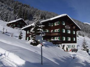 un gran edificio en la nieve con un cartel delante en Brücklmeier Ferienwohnungen, en Gargellen