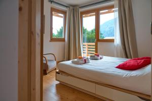 sypialnia z łóżkiem z czerwonymi poduszkami i oknem w obiekcie Casa al Sole Apt. 2 w mieście Pinzolo