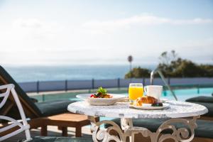 a table with a plate of food and two glasses of orange juice at Harbour House Hotel - Manor House in Hermanus