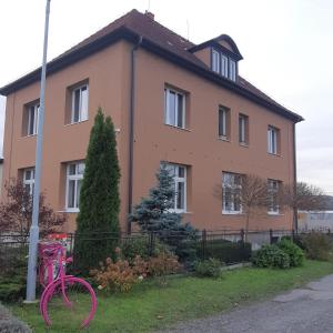 Una bicicleta rosa estacionada frente a una casa en Apartmán u Javorů, en Varnsdorf