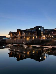 a building with a reflection in the water at night at Arctic Sea Hotel in Hammerfest