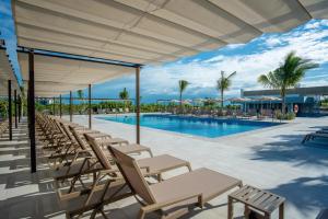 a swimming pool with lounge chairs and a swimming poolvisorvisor at Riu Latino - Adults Only - All Inclusive in Costa Mujeres