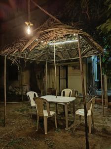 a table and chairs under a thatch roof at Mauli Cottage in Kashid