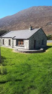 una casa de piedra en un campo de césped verde en Kearneys Cottage, Dugort, Achill Island, County Mayo - 3 Bedroom Sleeps 6, en Bellanasally