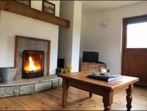 een woonkamer met een open haard en een houten tafel bij Kearneys Cottage, Dugort, Achill Island, County Mayo - 3 Bedroom Sleeps 6 in Bellanasally