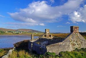 Bellanasally的住宿－Kearneys Cottage, Dugort, Achill Island, County Mayo - 3 Bedroom Sleeps 6，一座古老的石头建筑,毗邻水体