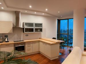 a kitchen with white cabinets and a large window at Panoramic Apartment Vilnius in Vilnius