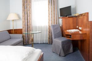 a hotel room with a bed and a desk and a tv at Hotel Dietmayr in Neumarkt in der Oberpfalz