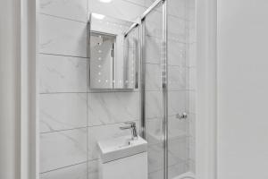 a white bathroom with a sink and a mirror at Heathrow Airport Studios with En-Suite in Southall