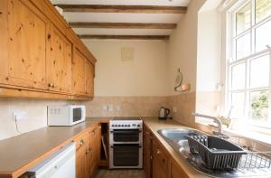 una cocina con armarios de madera y fregadero en The Old Cart Shed in the Peak District, en Bakewell
