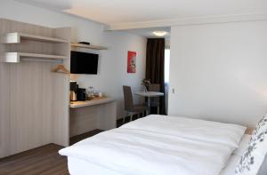 CudrefinにあるAuberge de La Saugeの白いベッドとデスクが備わるホテルルームです。