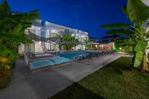 a villa with a swimming pool at night at Adonis Luxury Village in Pefkochori