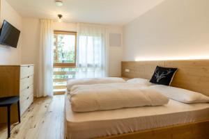 a bedroom with two beds and a television and a window at Casa Erika in San Lorenzo di Sebato
