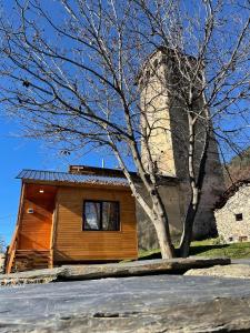 mały drewniany dom z drzewem przed nim w obiekcie Lavdila w mieście Mestia