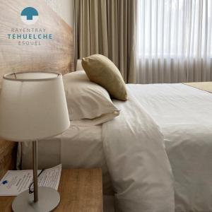Habitación de hotel con cama y mesa con lámpara en Hotel Tehuelche en Esquel
