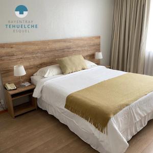 1 dormitorio con 1 cama grande y cabecero de madera en Hotel Tehuelche en Esquel