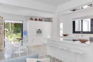 a white kitchen with white chairs and a table at Magical Ibizan Villa Walking Distance To The Beach Es Vedre Style 6 Bedrooms Fabulous Sea Views San Jose in Sant Josep de sa Talaia