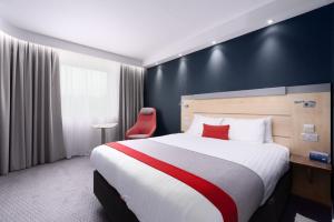 a hotel room with a large bed and a red chair at Holiday Inn Express Burnley M65 Jct 10, an IHG Hotel in Burnley