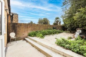 a garden with a chair and a brick wall at Heathrow Airport Studios with En-Suite in Southall