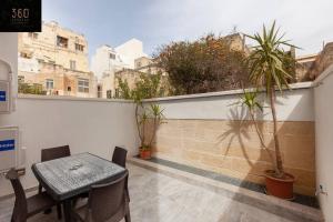 a table and chairs on a balcony with plants at Comfy APT with Terrace, 5 mins to Sliema Ferries by 360 Estates in Il-Gżira