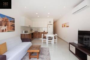 een woonkamer met een witte bank en een keuken bij Comfy APT with Terrace, 5 mins to Sliema Ferries by 360 Estates in Il-Gżira