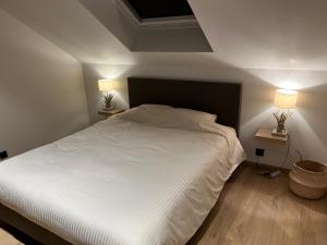 Gîte Chez Doumé في هوفاليز: غرفة نوم بسرير ابيض كبير ومصباحين