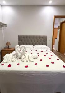 a bed with a white bedspread with roses on it at Casa do Alto Santa Mônica- Natureza ao seu redor in Itaipava