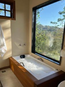 a bath tub in a bathroom with a large window at Casa do Alto Santa Mônica- Natureza ao seu redor in Itaipava
